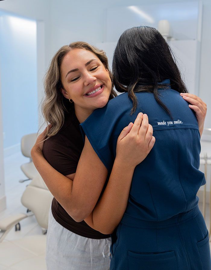 Canary Dental patient happily hugging Doctor Lamba after treatment in a bright clinic room