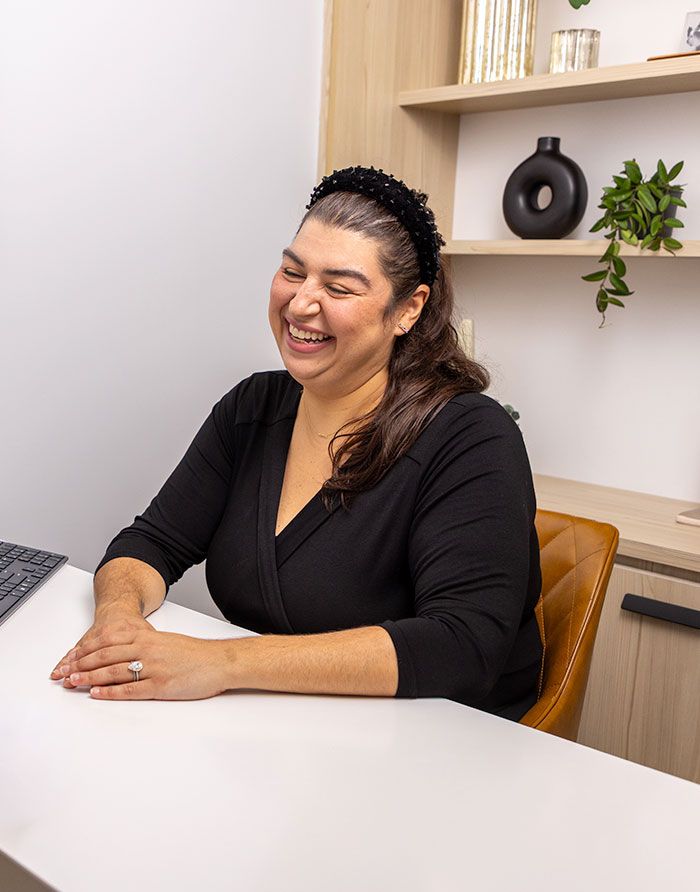 canary-dental-general-dentistry-dental-care-experience-6 Canary Dental staff member smiling warmly while seated at a modern office desk