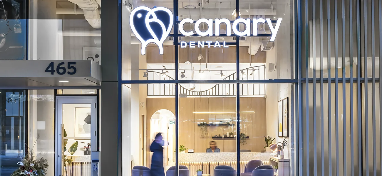 Canary Dental modern clinic exterior with illuminated logo and inviting interior visible through glass façade